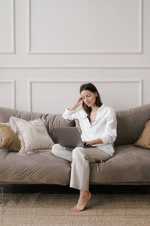 Vrouw met laptop op de bank in een lichte woonkamer