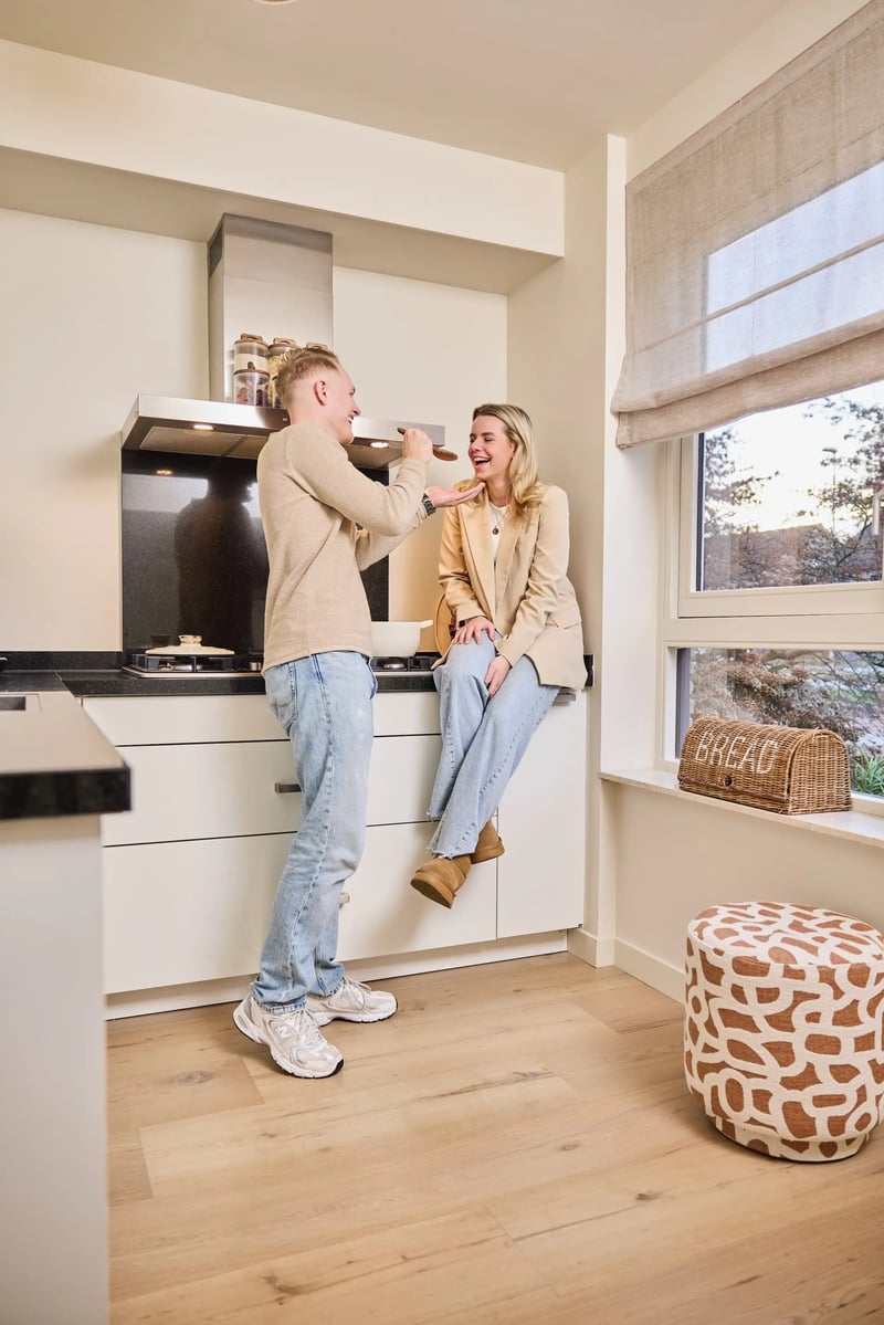 Stel met een lachende man en vrouw in een lichte keuken met houten vloer